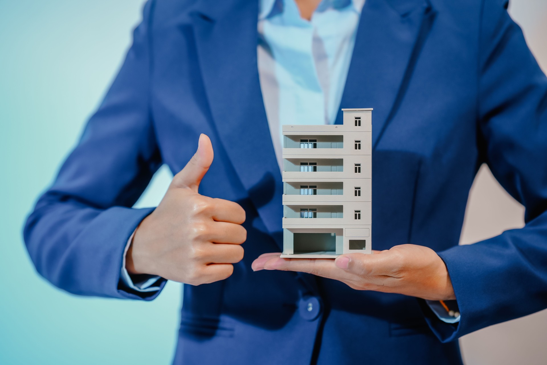 A female employee works at her desk in a real estate office, managing condo sales in the city. She communicates with clients, handles listings, and provides information about available properties